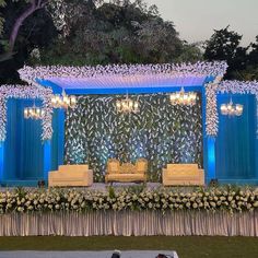 a decorated stage with couches and chandeliers for an outdoor wedding or reception