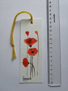 a watercolor painting of red flowers on a white background next to a measuring ruler