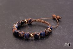 This Shamballa bracelet is a celebration of the natural beauty and vibrant culture of St. Croix. The unique blue and orange Sodalite cube beads evoke the island's crystal-clear waters and fiery sunsets. Each bead is carefully selected for its depth of color and natural variations, ensuring that no two bracelets are alike. Adorning the bracelet are gleaming gold discs, inspired by the shimmering golds of island sunsets. These discs add a touch of elegance and glamour to the piece, while also serving as a reminder of the island's rich history and cultural heritage. Together, the Sodalite beads and gold discs create a sense of balance and harmony, much like the island of St. Croix itself. This Shamballa bracelet is a statement piece that captures the essence of this stunning Caribbean paradis Adjustable Hand-strung Lapis Lazuli Bracelets, Blue Spiritual Braided Bracelets Hand-strung, Adjustable Lapis Lazuli Bracelet With Round Beads, Adjustable Lapis Lazuli Beaded Bracelets, Adjustable Lapis Lazuli Gemstone Beaded Bracelets, Adjustable Lapis Lazuli Beaded Bracelets Bohemian Style, Bohemian Lapis Lazuli Beaded Bracelets As Gift, Adjustable Lapis Lazuli Bracelet With 8mm Beads, Sodalite Round Beads Bracelets As Gifts