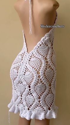 a white crocheted dress with tassels on the back