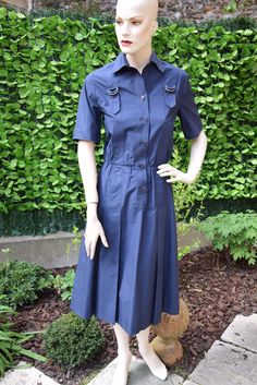 Nice classical navy blue poeppeline cotton shirt dress with short sleeves embellished with a strap motif which begins and ends at back in two inverted pleats, the chest adorned with two metal buckles. Closure by signed buttons. French size 38, American 6, International M. Very good vintage condition. More pictures on my website www.that-little-pink-shop.fr No discount. Free worldwide shipping with tracking and insurance. No returns, including EEC customers. Please contact if you have a problem w Formal Short Sleeve Shirt Dress With Pockets, Navy Button-up Workwear Dress, Navy Button-up Dress For Work, Classic Fitted Shirt Dress With Pockets, Formal Short Sleeve Buttoned Dress, Elegant Navy Shirt Dress For Summer, Formal Short Sleeve Dress With Buttons, Formal Cotton Dresses With Pockets, Formal Cotton Dress With Buttons