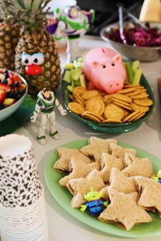 a table topped with plates filled with cookies and crackers next to bowls of fruit