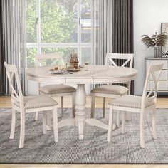 a white table and chairs in front of a window with an area rug on the floor