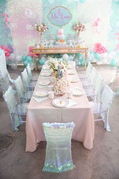 a table set up for a mermaid themed birthday party with balloons, plates and decorations