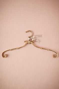 a gold metal hanger with two white flowers on it's end and an attached hook