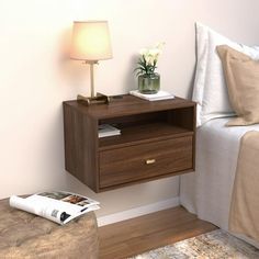 a nightstand with two drawers and a lamp on top of it next to a bed