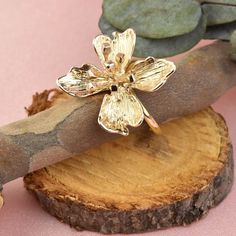 a gold flower ring sitting on top of a piece of wood