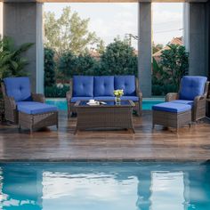 an outdoor living area with blue cushions and furniture by the pool in front of a house