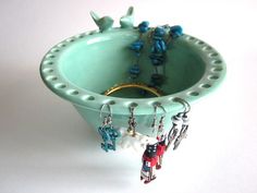 there is a bowl with beads in it and some earrings hanging from the rims