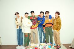 group of young men standing next to each other in front of a table with food and drinks on it