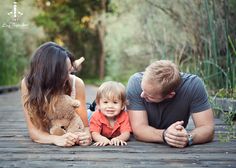 a man, woman and child laying on the ground with a teddy bear