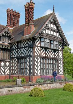 an old building with black and white stripes on it's walls, surrounded by green grass