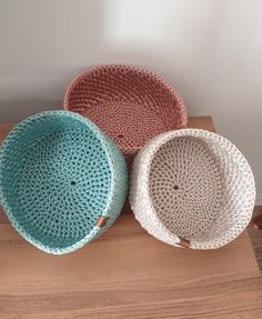 three crocheted baskets sitting on top of a wooden table