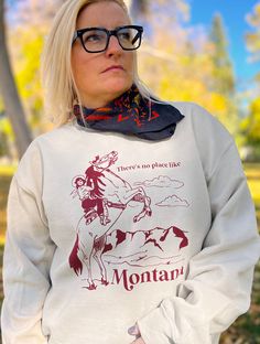 There's no place like Montana. Super cute cozy unisex sized crew neck sweatshirt featuring a cowgirl on a bucking horse. Perfect for your trip to the ranch, apres ski at Big Sky or sipping cocoa in front of a fireplace. Unisex sized sweatshirt has a loose comfortable feel and is hand screen printed with Earth friendly water based inks.  Available in sizes Small Medium Large XLarge **more sizes available upon request** Makes a great gift for the skiers, hikers and outdoor lovers! This print is also available in tea towels, totes and in a gift set! Fall Crew Neck Sweatshirt For Adventure, Letter Print Sweatshirt For Fall Adventure, Fall Adventure Letter Print Sweatshirt, Western Style Crew Neck Tops For Fall, Graphic Print Sweatshirt For Fall Adventures, Red Crew Neck Sweatshirt For Outdoor, Cowgirl On Horse, Montana Cowgirl, Montana Sweatshirt