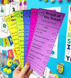 someone is holding up four colorful tickets for the school's valentine day program in front of their classroom bulletin board