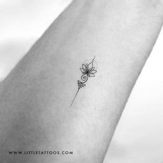 a small flower tattoo on the wrist is shown in black and white, with a spiral design