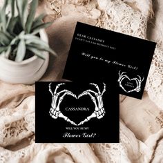 two black and white wedding cards sitting on top of a bed next to a potted plant