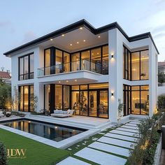 a large white house with lots of windows next to a swimming pool and grass area