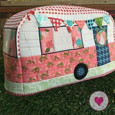 a pink bus shaped pillow sitting on top of grass