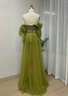 a green dress on a mannequin in front of a white wall with curtains