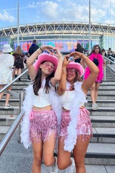 two women in pink and white outfits standing on steps with their arms around each other