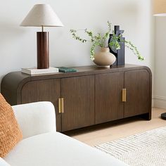 a living room with a couch, table and lamp on it's sideboard