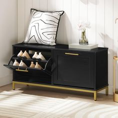 a black cabinet with gold trim holds shoes and a white pillow on the floor next to it