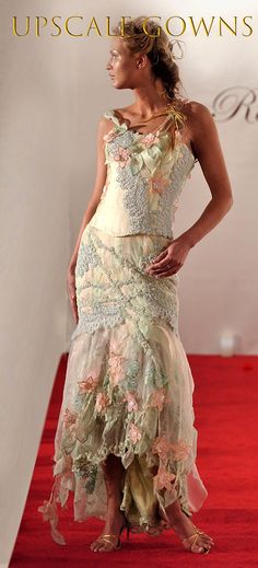 a woman is walking down the red carpet wearing a dress with flowers and leaves on it