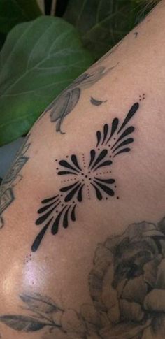 a close up of a person's arm with tattoos on it and flowers in the background