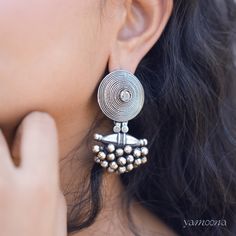 The Niovi Abheer Silver Earrings with an oxidised finish showcase a captivating blend of intricate design and vintage allure. The darkened patina enhances their detailed craftsmanship, offering a unique and elegant statement piece that complements both traditional and modern styles. Elegant Antique Finish Earrings For Festive Occasions, Oxidized Metal Earrings For Celebration, Ornate Oxidized Earrings For Festive Occasions, Ornate Oxidized Finish Festive Earrings, Ornate Oxidized Chandbali Jhumkas, Ornate Oxidized Chandbali Jewelry, Ornate Chandbali Oxidized Jhumkas, Ornate Chandbali Jhumkas With Oxidized Finish, Elegant Oxidized Earrings For Ceremonial Occasion