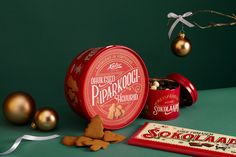 an assortment of christmas cookies and candy in tins on a green table with ornaments