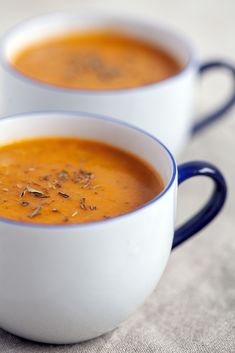 two white bowls filled with soup on top of a table