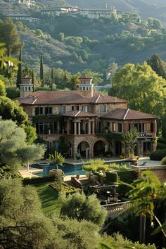 a large house surrounded by lush green trees and mountains in the distance is an outdoor swimming pool