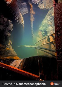 the water is very clear and blue in this underwater scene, with pipes sticking out from the ground