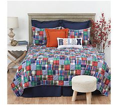 a bed with blue, red and green plaid bedspread on top of it