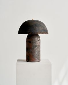 a metal lamp sitting on top of a white block in front of a white wall