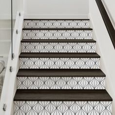 the stairs are decorated with black and white geometric tiles, along with wood handrails