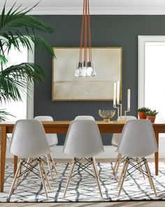 a dining room table with white chairs and a painting on the wall