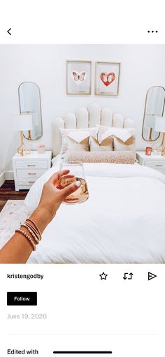 a person is holding an object in their hand while sitting on a bed with white linens