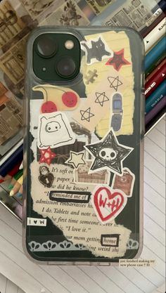 an iphone case with stickers on it sitting on top of a pile of books