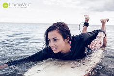 a woman laying on top of a surfboard in the water with her arms out