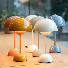 four different colored lamps sitting on top of a wooden table