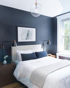 a bedroom with blue walls and white bedding