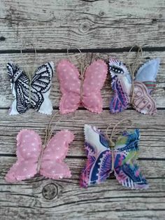 four different colored butterflies are hanging from twine strings on a wooden surface with string attached to them