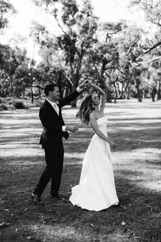 a bride and groom dancing in the park