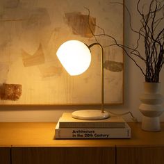 a table lamp sitting on top of a book next to a vase