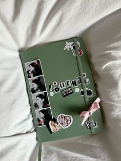 a green binder with pictures and stickers on it sitting on top of a bed