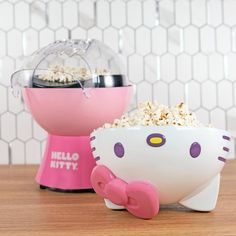 a hello kitty bowl with popcorn in it sitting on a table next to a pink mixer