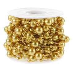 gold colored beads are spooled together on a white surface, with one bead in