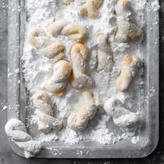 powdered doughnuts and pastries on a baking tray with powdered sugar